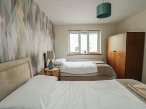 Habitación de hotel con dos camas, una ventana con vistas, un armario y una lámpara en una mesita de noche.