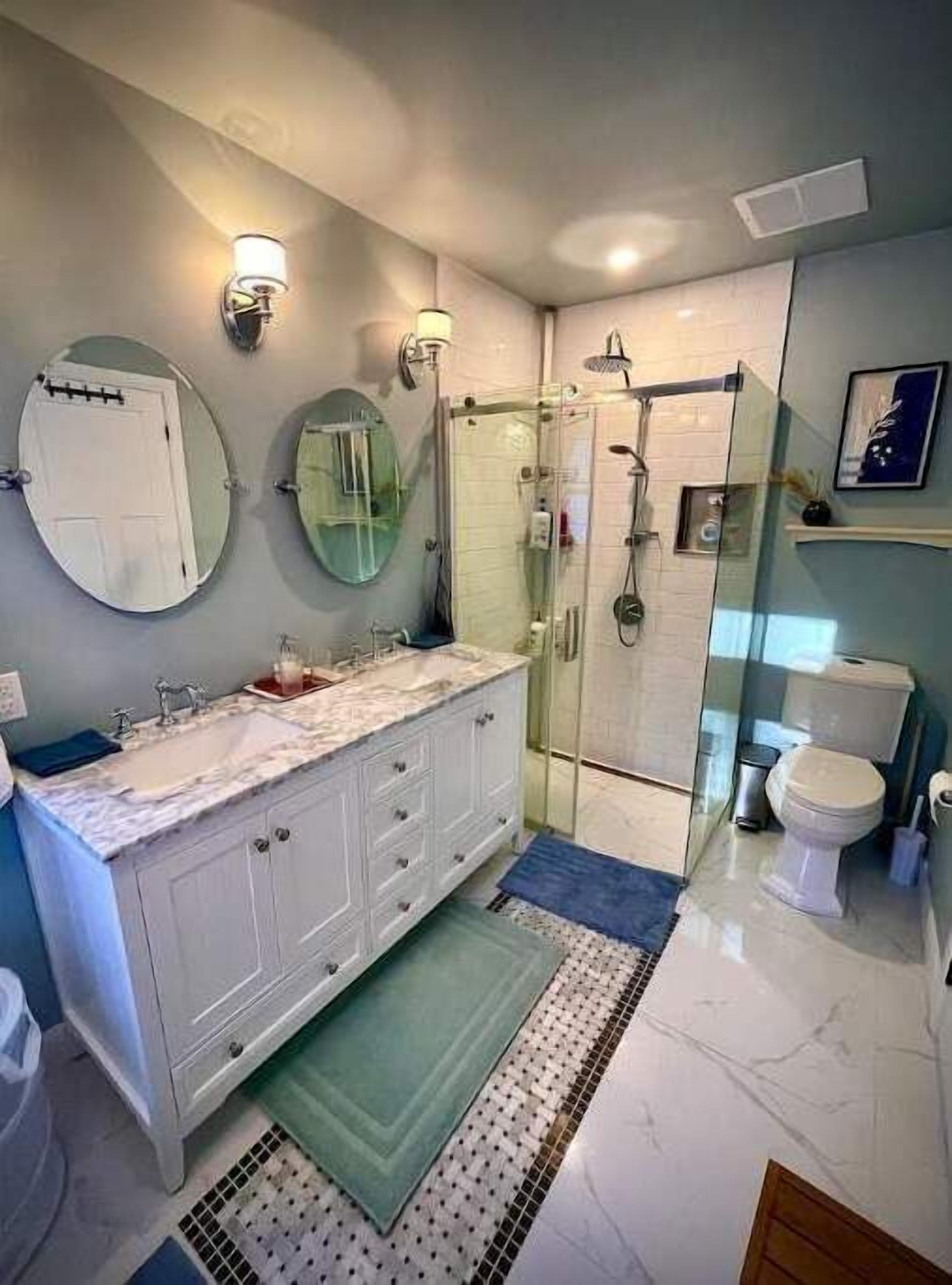 A modern bathroom with a white vanity, a glass shower enclosure, and a toilet.