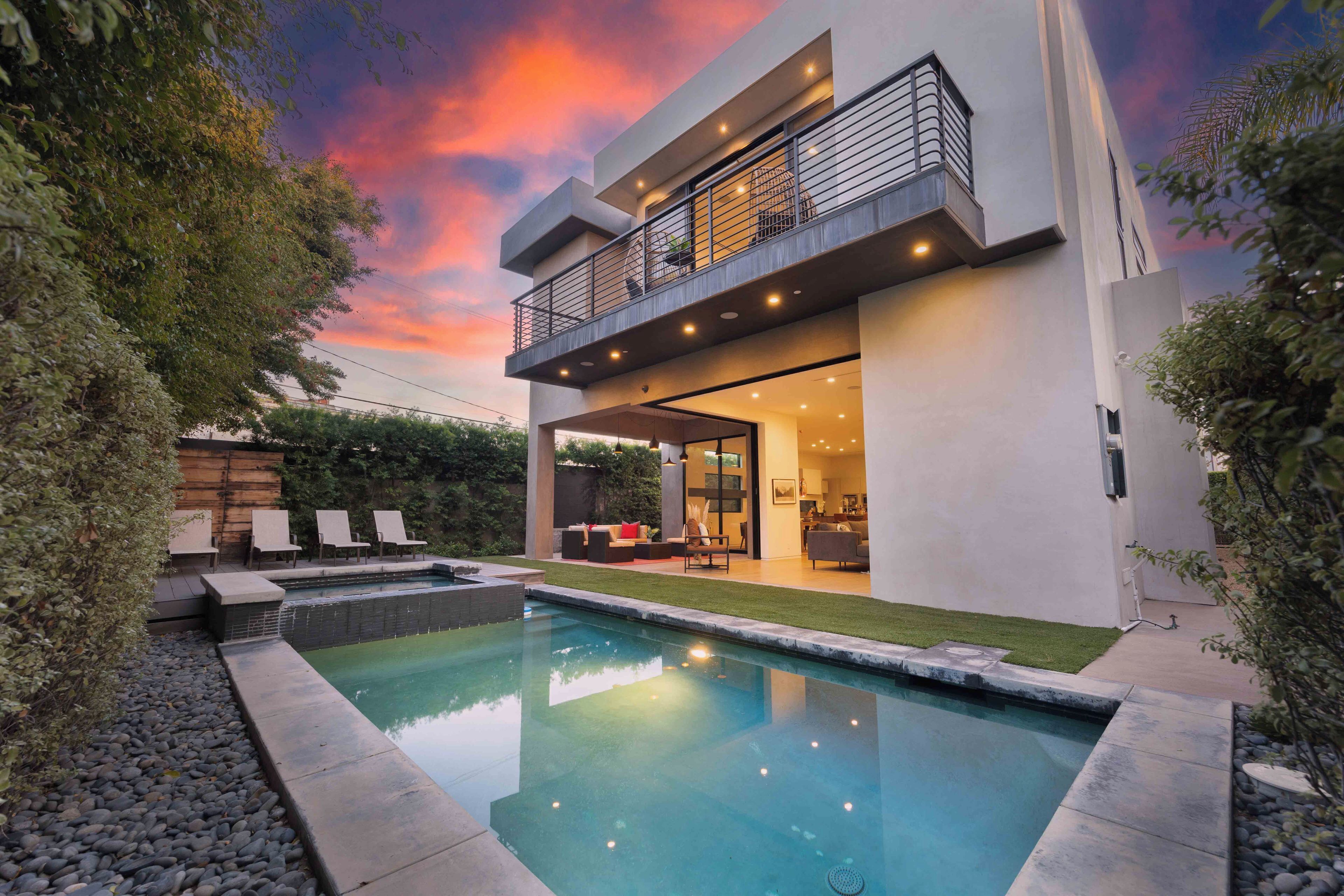 A modern two-story house with a swimming pool, outdoor seating, and a balcony.