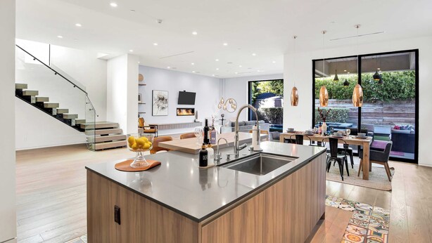 A modern kitchen with a central island, a dining area with a large window, and a staircase leading to another level. - LA Villa by Avantstay Walk to The Grove LA (Los Angeles)