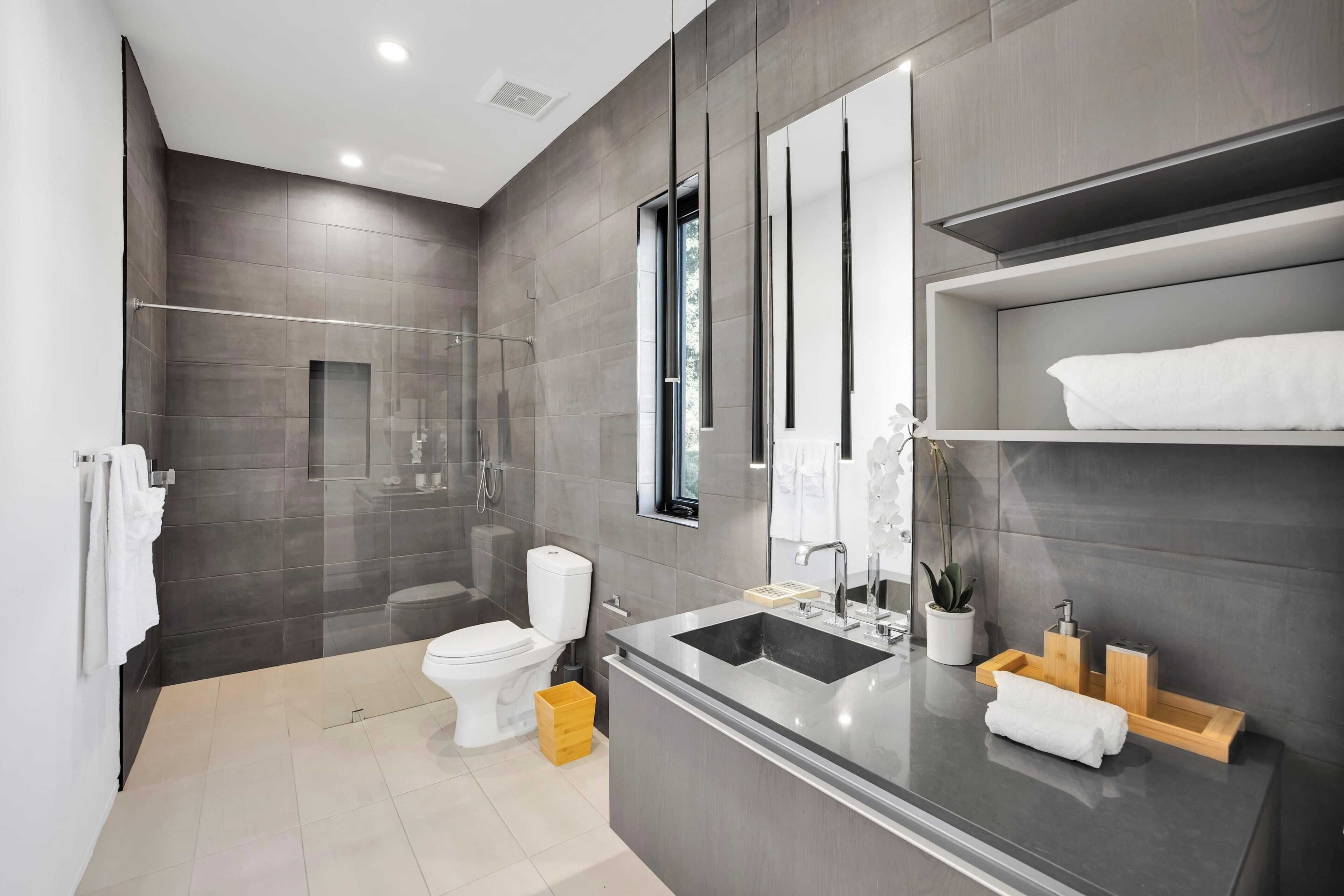 Un baño moderno con un espejo grande, un lavamanos integrado y una zona de ducha.