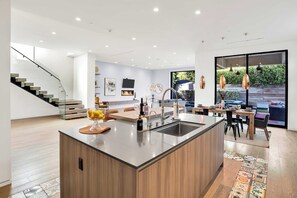 Une cuisine moderne dotée d’un îlot central, d’un coin repas avec une table et des chaises, et d’un escalier menant à un autre niveau.