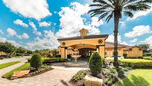 A yellow building with a fountain in front, surrounded by well-maintained landscaping and palm trees.