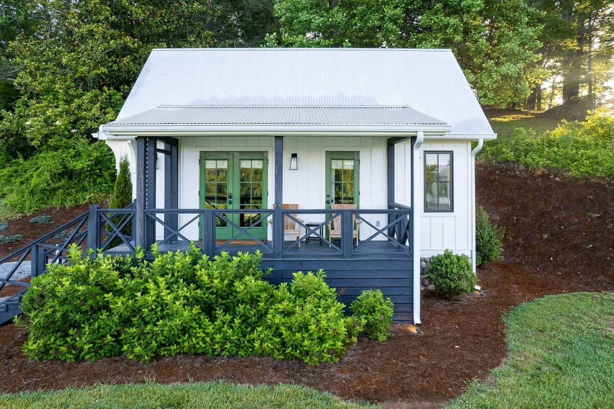 A single-story house with a porch, a green door, and a small garden area.