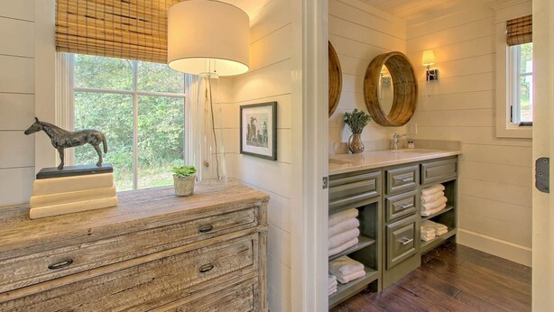 Une salle de bain avec un meuble-lavabo en bois, une sculpture de cheval, un tableau encadré et un grand miroir.
