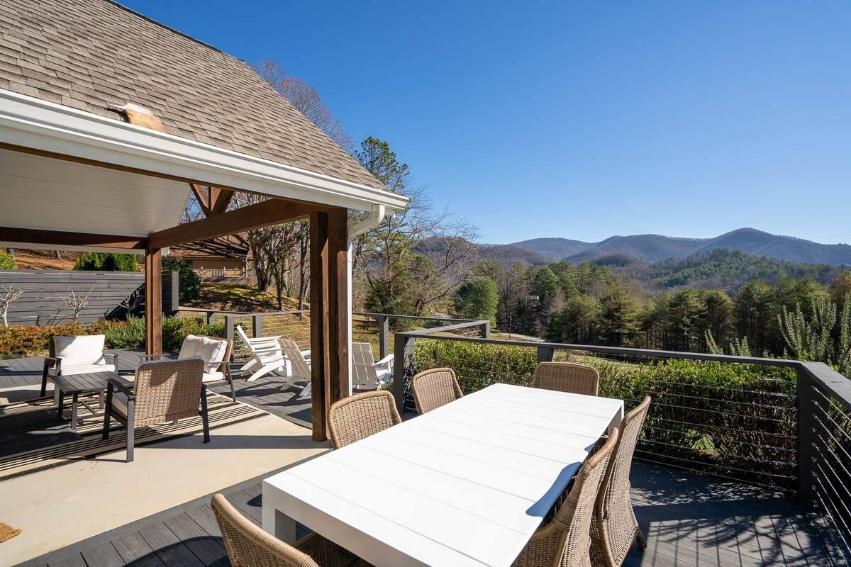 An outdoor patio with a table and chairs, overlooking a mountainous landscape.