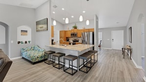 Une cuisine spacieuse dotée d’un îlot central, de meubles en bois et d’appareils électroménagers modernes.