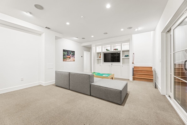 A modern living room with a sectional sofa, a television, and a play area with toys.