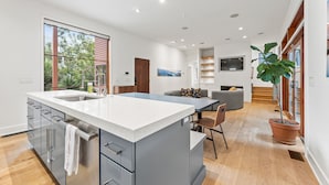A modern kitchen with a large island, built-in appliances, and a view of the outdoors. - The Red House in Serenbe w/ Golf Cart (Palmetto)