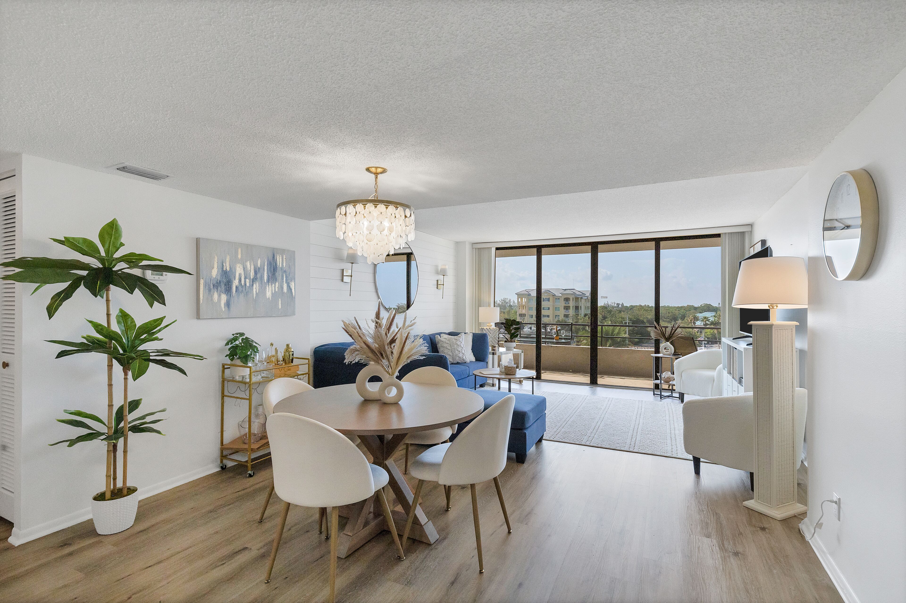 A modern living room with a dining area, large windows, and a view of the city.