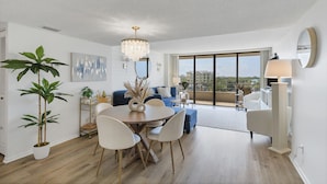 Ein modernes Wohnzimmer mit Essbereich, großen Fenstern und Blick auf die Stadt.