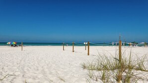 Ein Strand mit weißem Sand, blauem Himmel und einer Seilsperre.