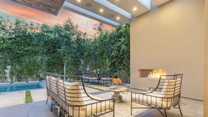 Un patio moderno al aire libre con piscina, zona de estar y una chimenea.