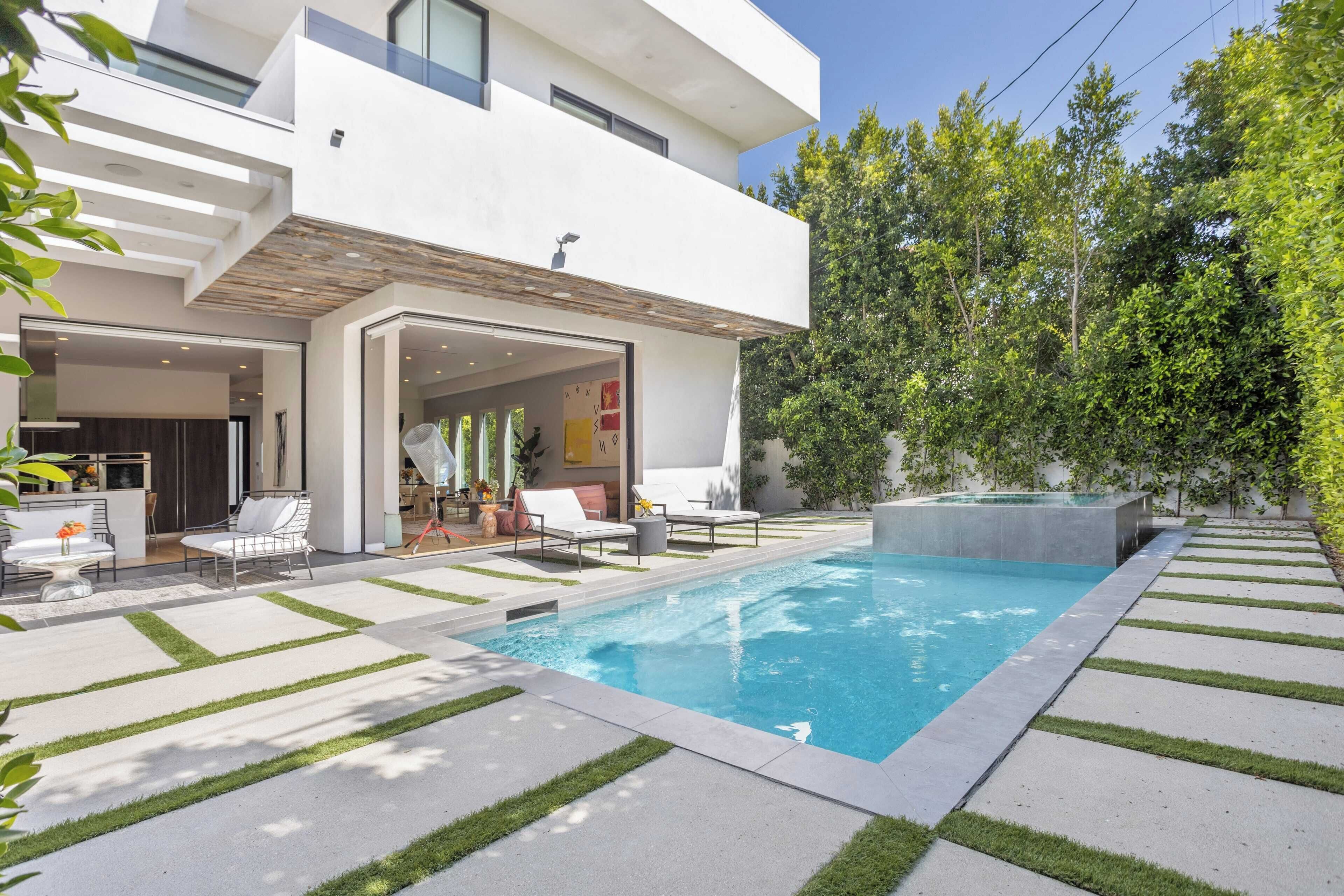 Ein modernes Haus mit Swimmingpool, Sitzgelegenheiten im Freien und einem gepflegten Garten.