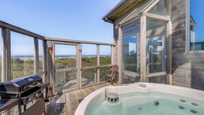 Eine Holzterrasse mit Whirlpool, Grill und einem Stuhl mit Blick auf eine schöne Landschaft.