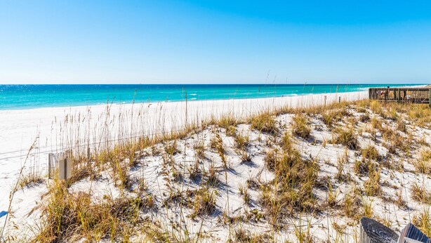 A beach with white sand, clear blue water, and a wooden boardwalk. - Starboard Village by Southern Vacation Rentals (Pensacola Beach)