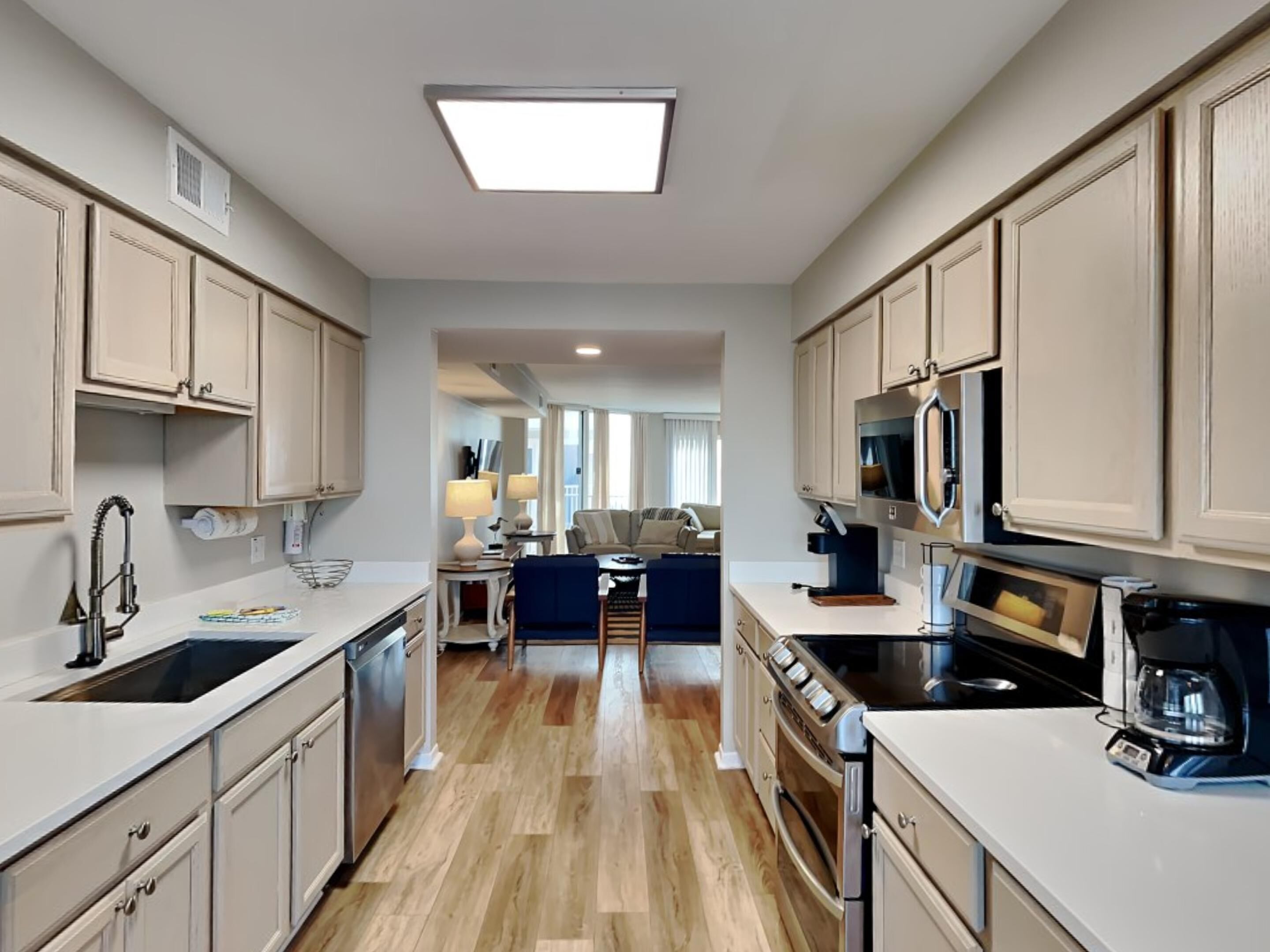 A modern kitchen with white cabinetry, a central island, and a dining area with a sofa and table.