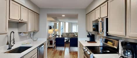 A modern kitchen with white cabinetry, a central island, and a dining area with a sofa and table.