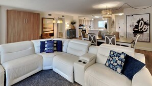 A modern living room with a sectional sofa, a dining area, and a kitchen in the background. - Starboard Village by Southern Vacation Rentals (Pensacola Beach)