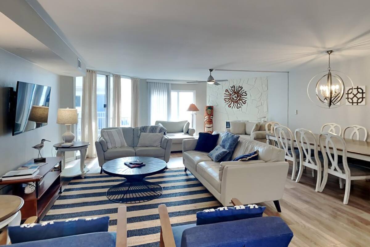 Un salon moderne comprenant un canapé, des fauteuils, une table basse et un coin repas avec des chaises.