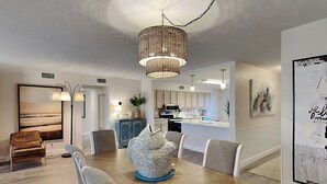 A modern dining area with a wooden table, white chairs, and a decorative centerpiece. - Starboard Village by Southern Vacation Rentals (Pensacola Beach)