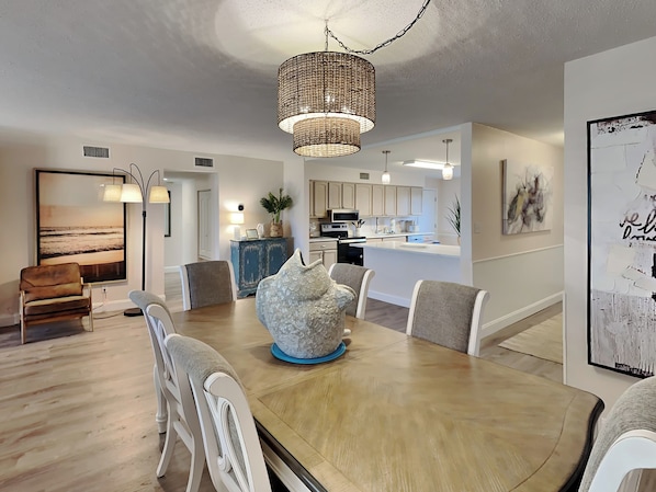 A modern dining area with a wooden table, white chairs, and a decorative centerpiece.