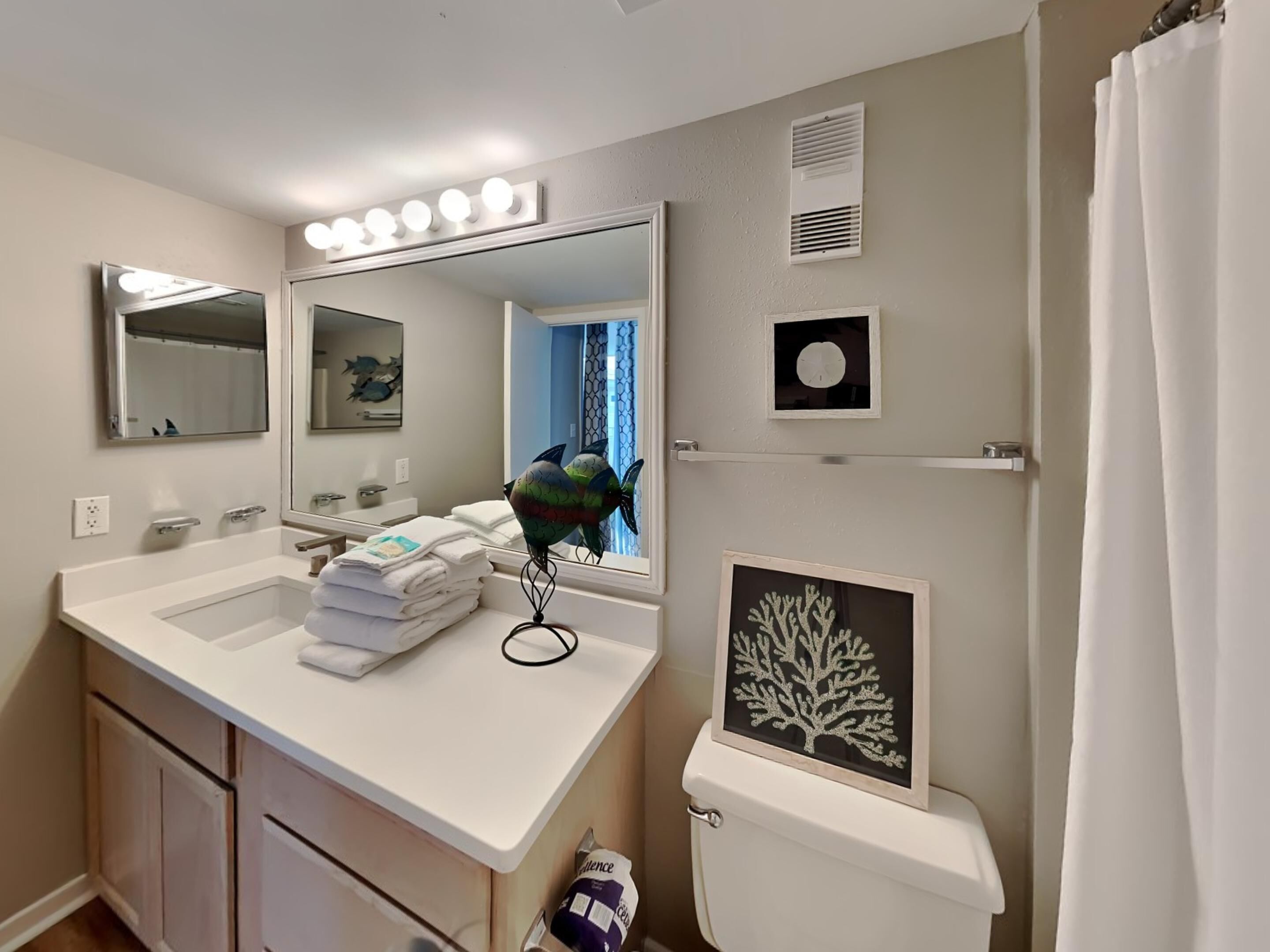 A bathroom with a white sink, two mirrors, a vanity, and a toilet.