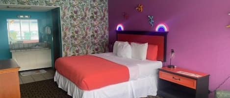 A hotel room with a bed, a nightstand, a dresser, and a bathroom visible through an open door.