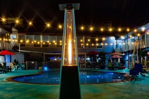 A swimming pool with a central water slide, surrounded by outdoor seating and umbrellas. - The District Hotel Club and Resorts (Oklahoma City)
