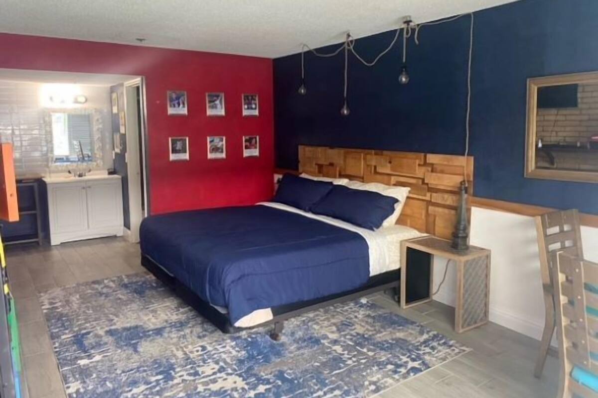 A bedroom with a bed, a dresser, a nightstand, and a mirror.