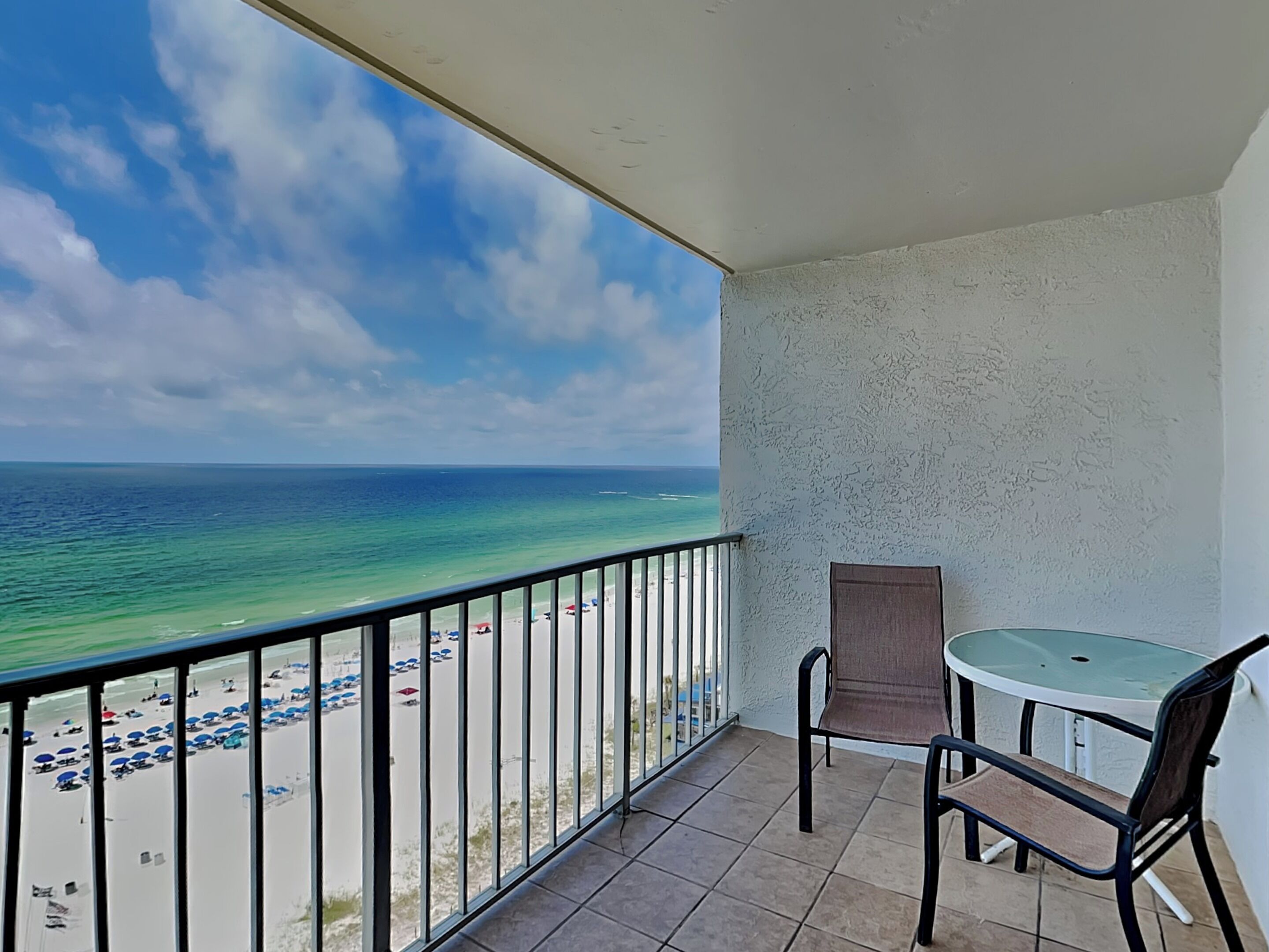 A balcony with a view of the beach and ocean.