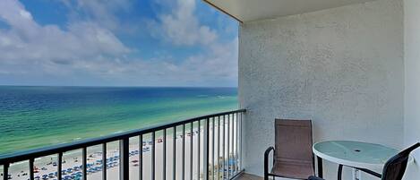 A balcony with a view of the beach and ocean.