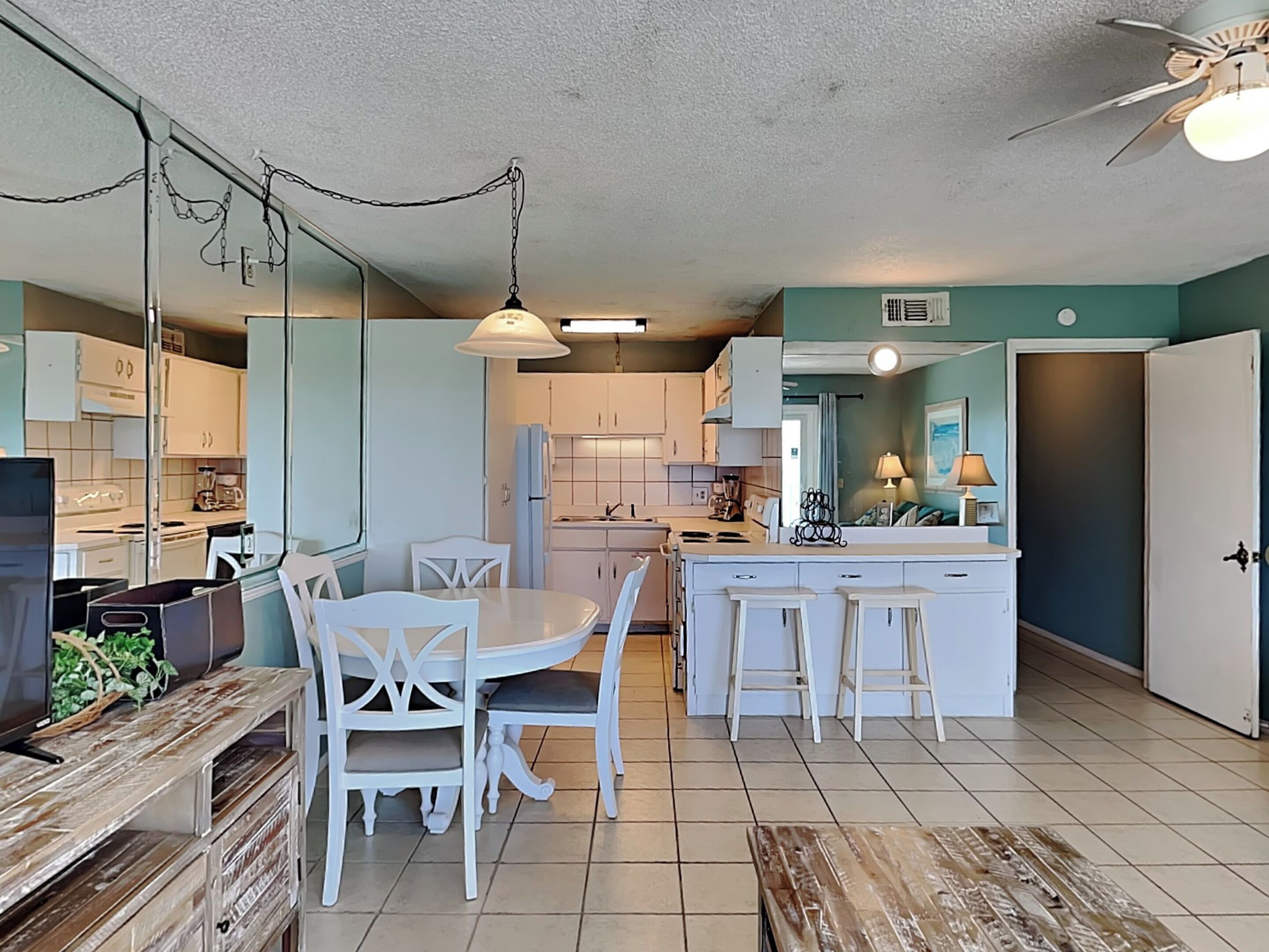 A compact kitchen with white cabinets, a dining table with chairs, and a small island with stools.