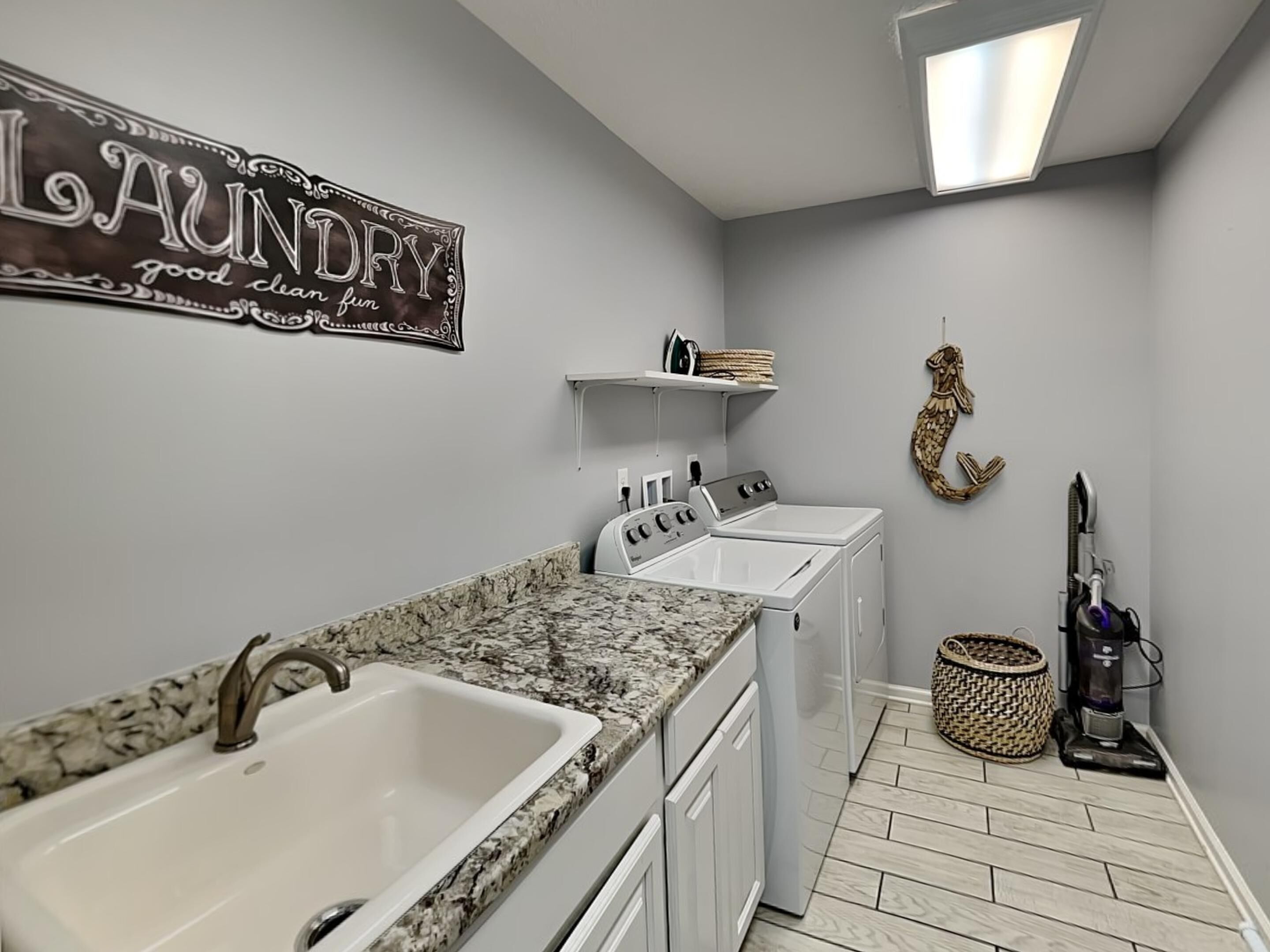 Ein Waschraum mit zwei Waschbecken, einer Waschmaschine, einem Trockner und einem Staubsauger.