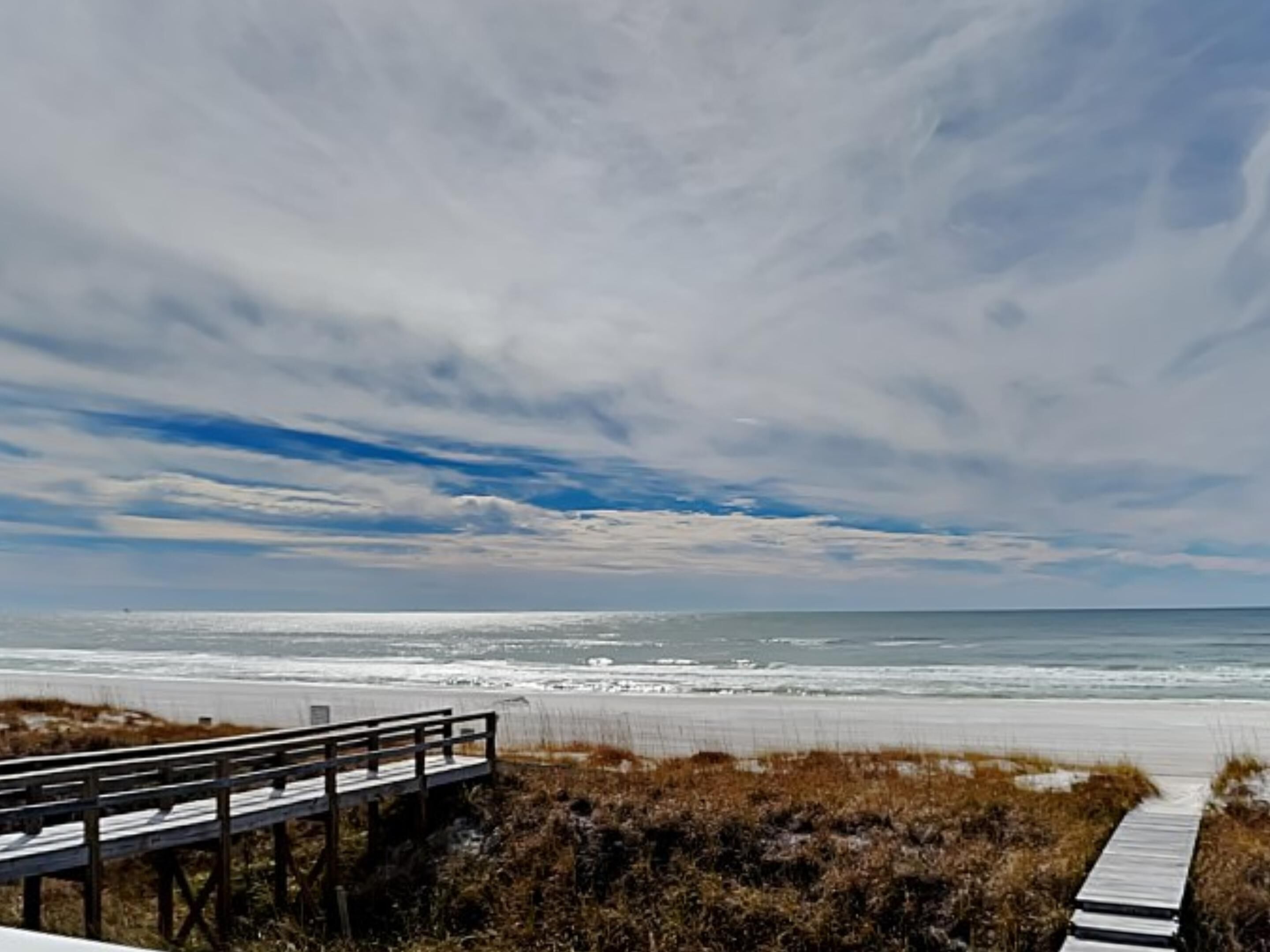 Ein Strand mit einer Holzpromenade, die zum Ufer führt.