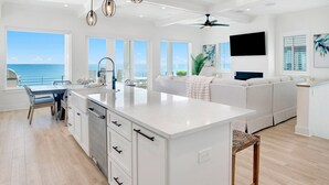 A spacious kitchen with a large island, white cabinetry, and pendant lighting.