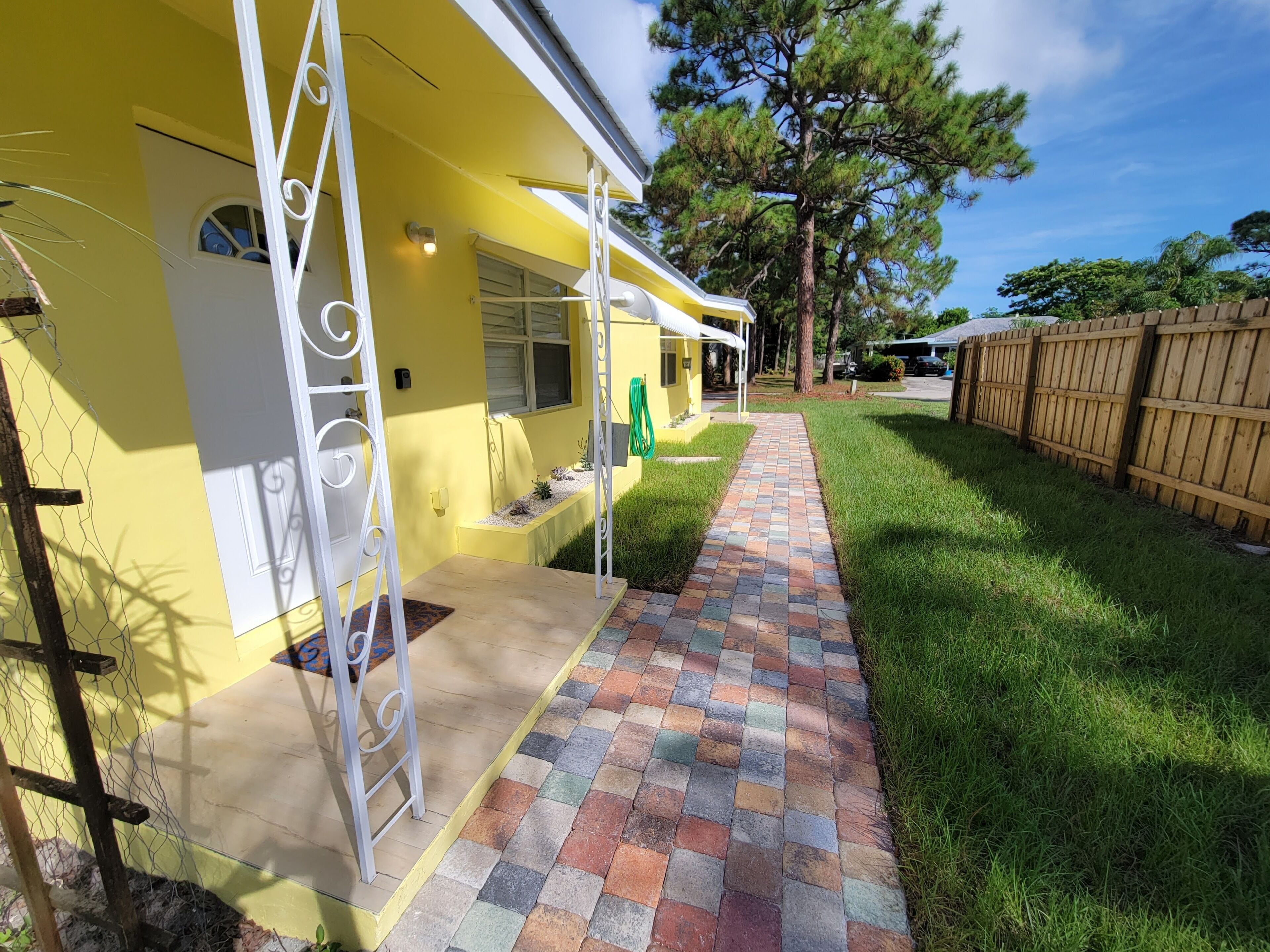 A yellow building with a brick pathway leading to a covered porch.