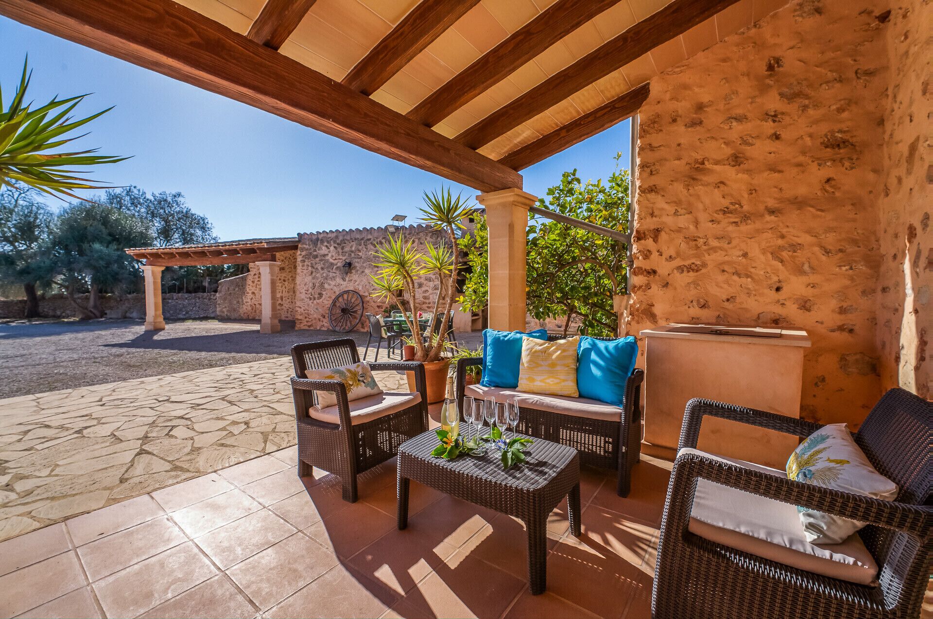 An outdoor patio with wicker furniture, a stone wall, and a pergola.