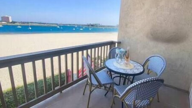Ein Balkon mit Tisch und Stühlen mit Blick auf einen Strand und Boote.