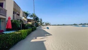 Ein Hotel am Strand mit Sandweg, Palmen und blauem Himmel.