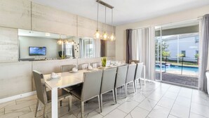 Un espace repas moderne avec une grande table, des chaises et un luminaire suspendu.