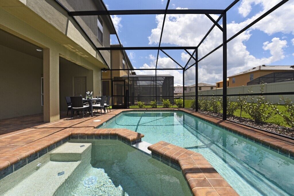A swimming pool with a sunken hot tub area, surrounded by a covered patio with outdoor furniture.
