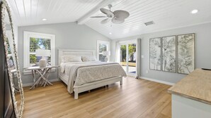 Une chambre à coucher avec un lit, un bureau, un ventilateur de plafond et des œuvres d’art accrochées au mur.