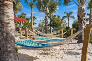 Relax in a serene beach setting with hammocks suspended between posts, offering a tranquil spot to unwind.