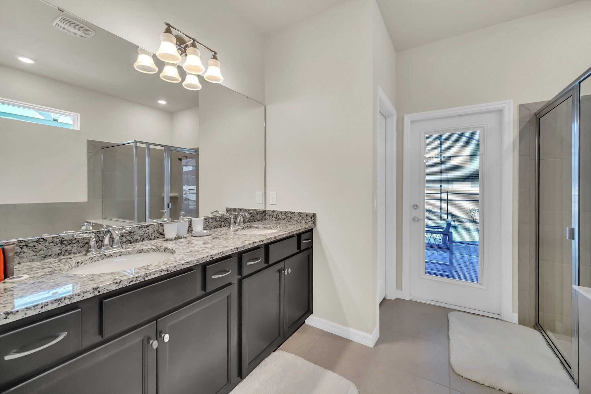 A modern bathroom with a large vanity, double sink, and a glass shower enclosure.