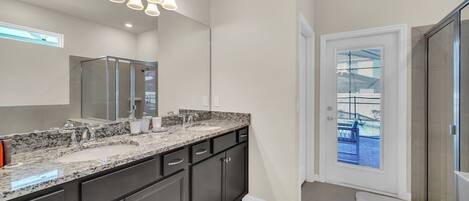 A modern bathroom with a large vanity, double sink, and a glass shower enclosure.