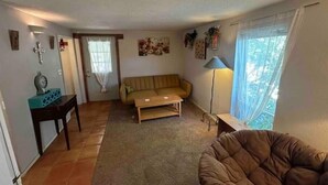 Una sala de estar con sofá, mesa de centro, lámpara y ventana con cortinas.