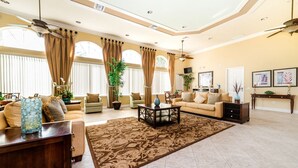 A spacious living room with a large brown rug, beige sofas, and a coffee table. - New Listing! Watersong Resort, 9mi to Disney & 18mi to Universal - FS54807 (Davenport)