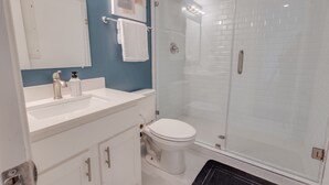 A bathroom with a white sink, a toilet, and a glass-enclosed shower. - 1 BR 1 BA Luxury - Museum District & Downtown HTX (Houston)