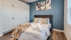 A bedroom with a bed, a large wardrobe, and abstract wall art. - 1 BR 1 BA Luxury - Museum District & Downtown HTX (Houston)